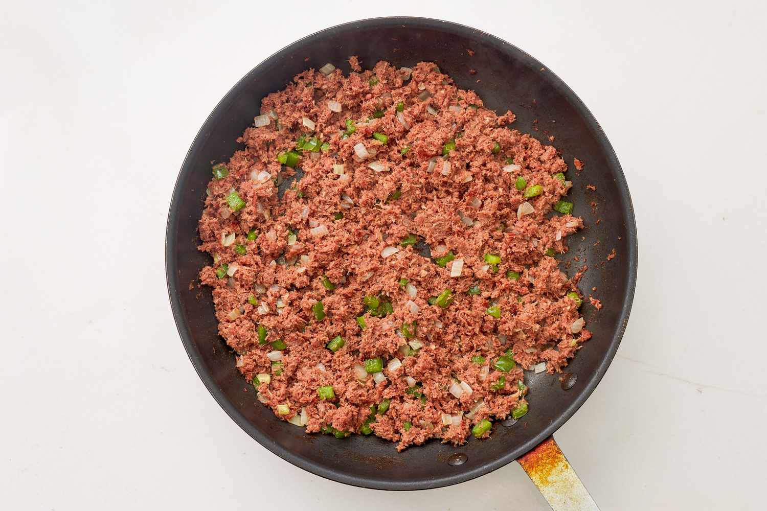 Corned beef and aromatics cooking in a skillet for corned beef tater tot casserole recipe