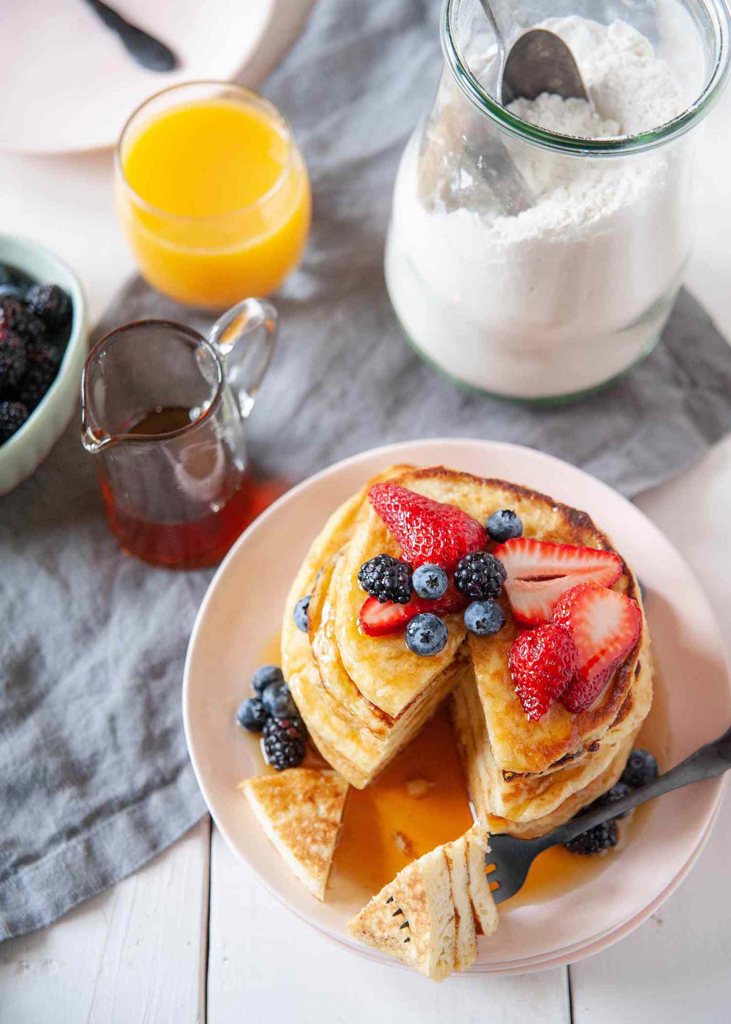 How to Make Pancake Mix - stack of pancakes drenched in syrup with berrieson top