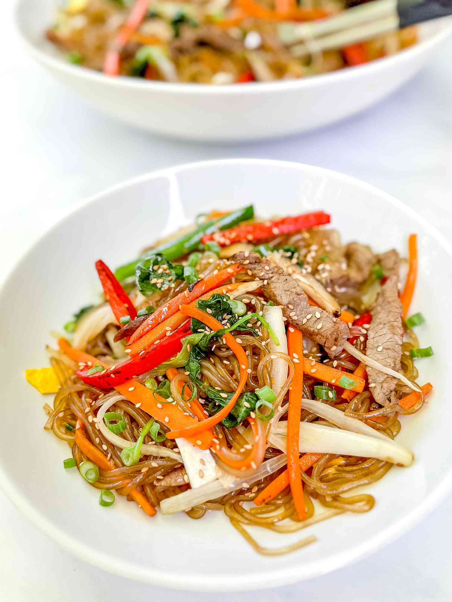japchae on a plate an more in a bowl in the background 