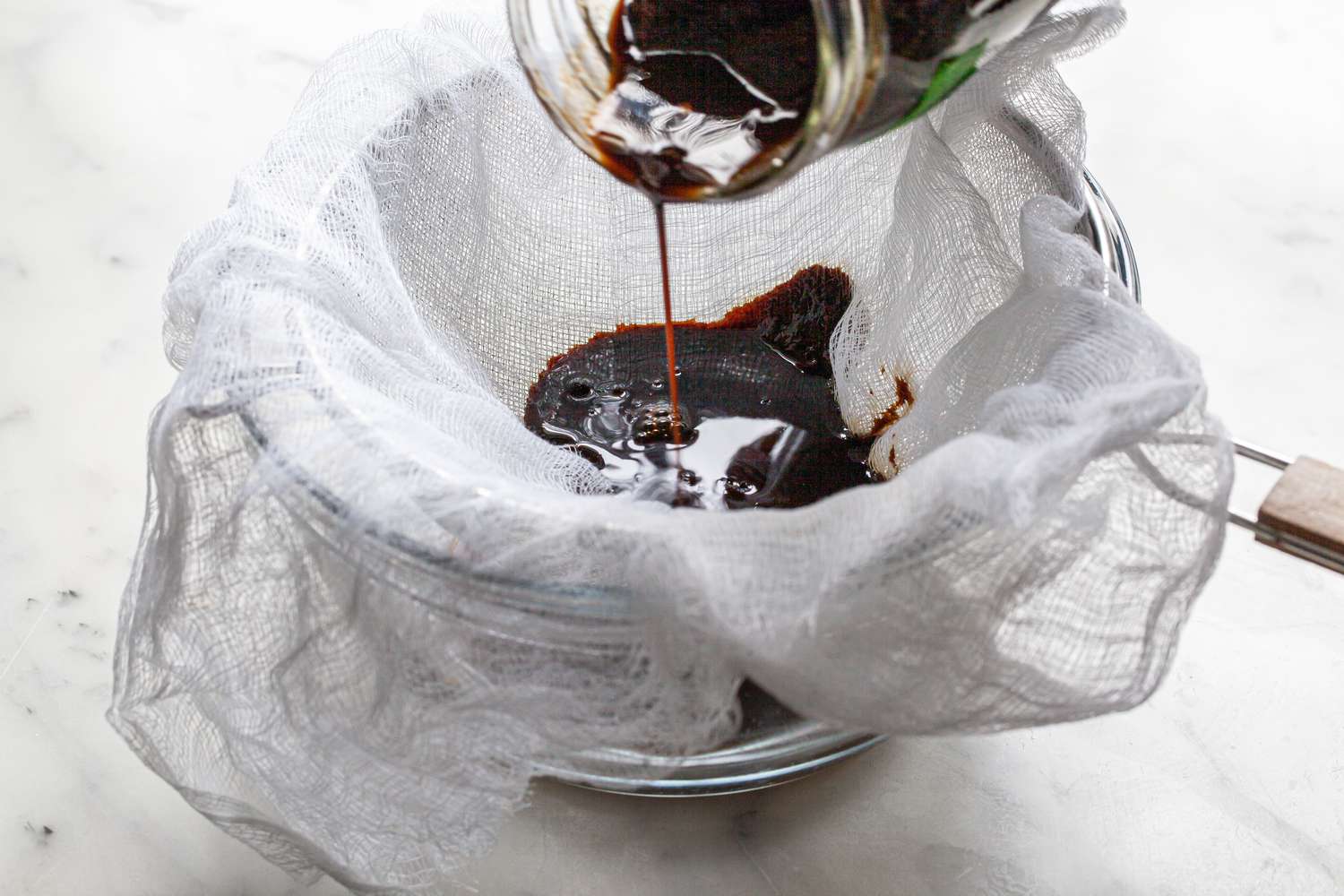 Worcestershire Sauce Strained into a Bowl Through a Cheese Cloth Lined Colander
