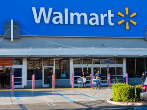 Exterior of a Walmart store with shoppers entering and exiting through sliding doors