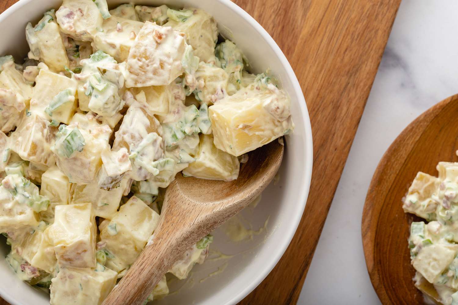 Potato salad in a bowl with a wooden spoon.