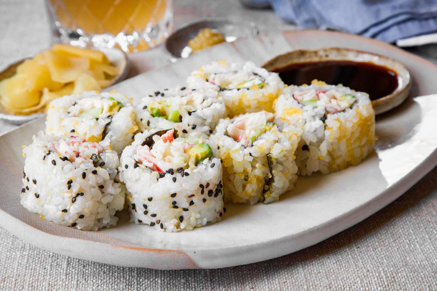 California Rolls on a Plate Next to a Small Bowl of Soy Sauce, Small Bowl of Pickled Ginger, and Small Saucer of Wasabi