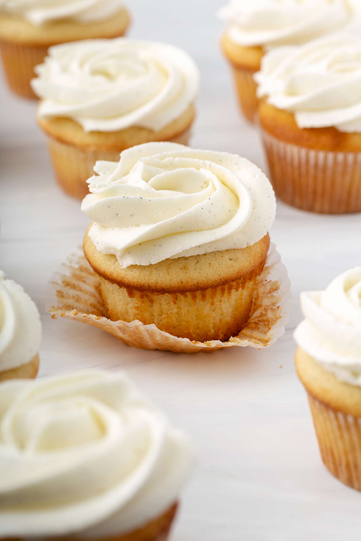 Side view of vanilla cupcakes with the wrapper pulled down from the center one of the best vanilla cupcake recipe.