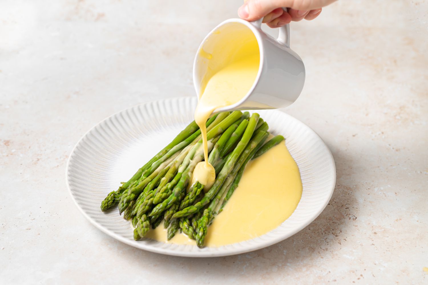 Blender Hollandaise Sauce poured over asparagus.
