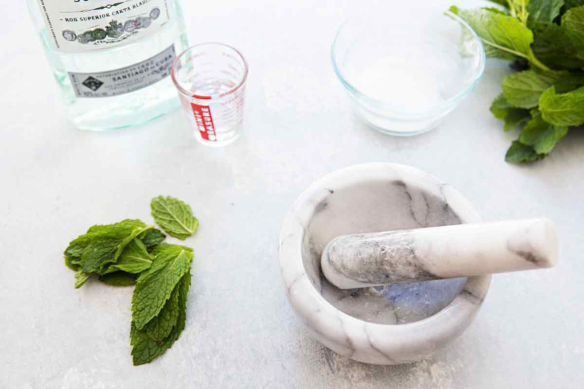 Mortar and pestle with fresh mint and rum on the side