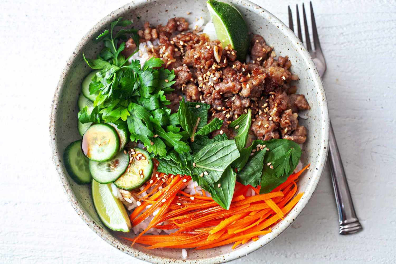 ginger pork rice bowl with vegetables in a bowl with a fork