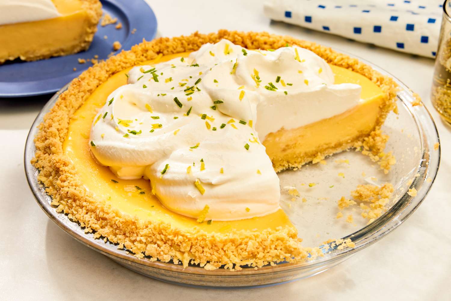 Atlantic Beach Pie with a slice removed, topped with whipped cream and garnished with lime zest in a glass pie dish