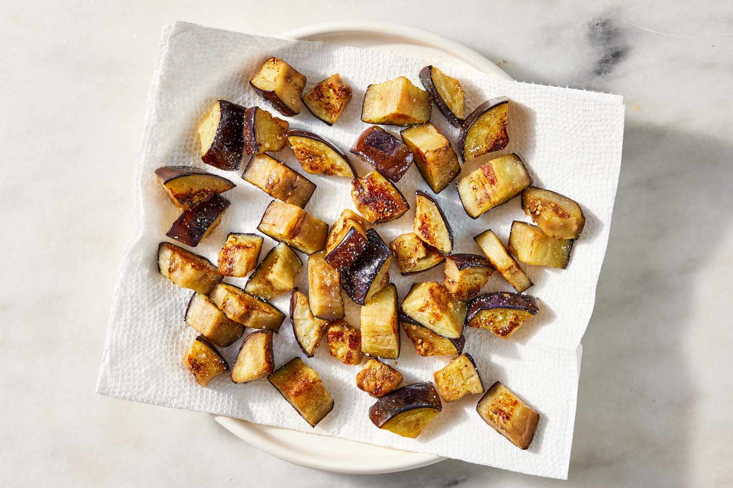 cooked eggplant pieces on a paper towel lined plate for pasta alla norma recipe