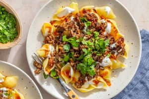 A plate of Turkish pasta topped with ground meat, yogurt, and fresh herbs