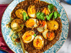 Plate of Egg Masala Curry with a Spoon on a Kitchen Linen