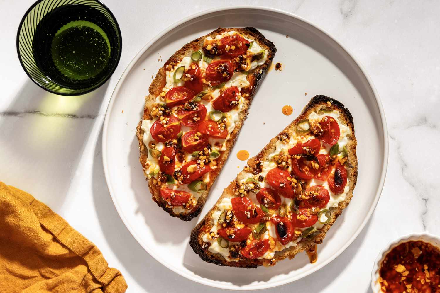 Cottage cheese toast topped with cherry tomatoes and green onions on a round plate