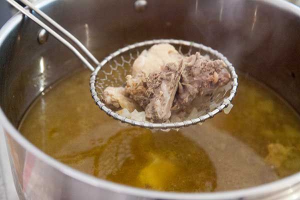 Straining chicken pieces out of chicken stock 
