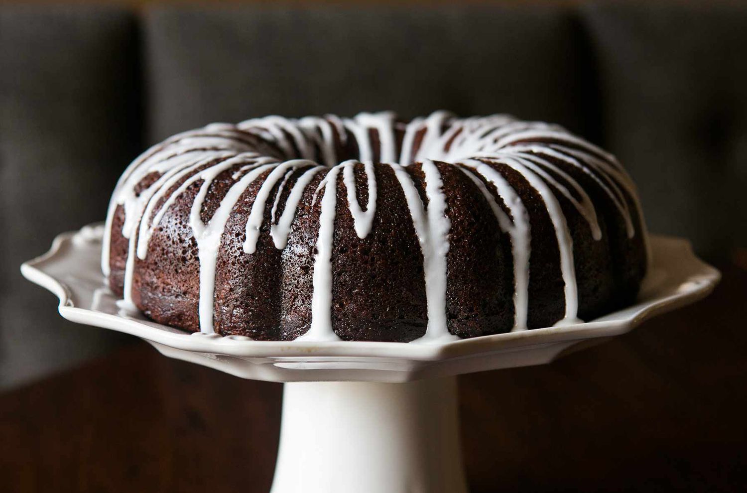 chocolate zucchini cake with sugar glaze on a white cake pedastal