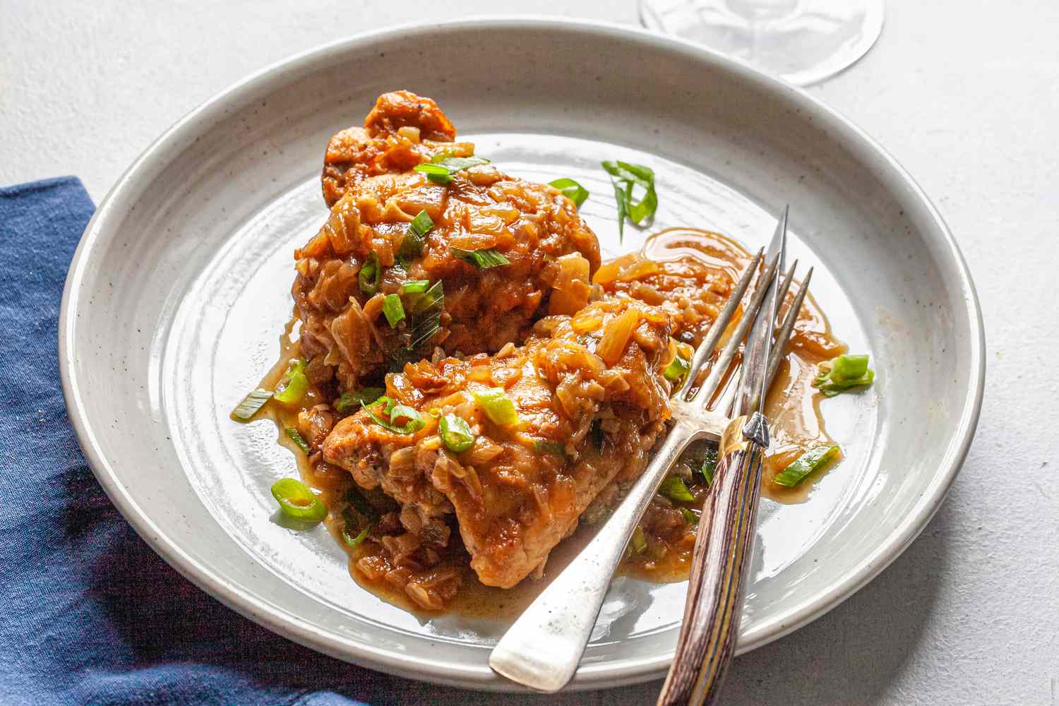 Comfort food classic: smothered chicken and gravy on a white plate with utensils.