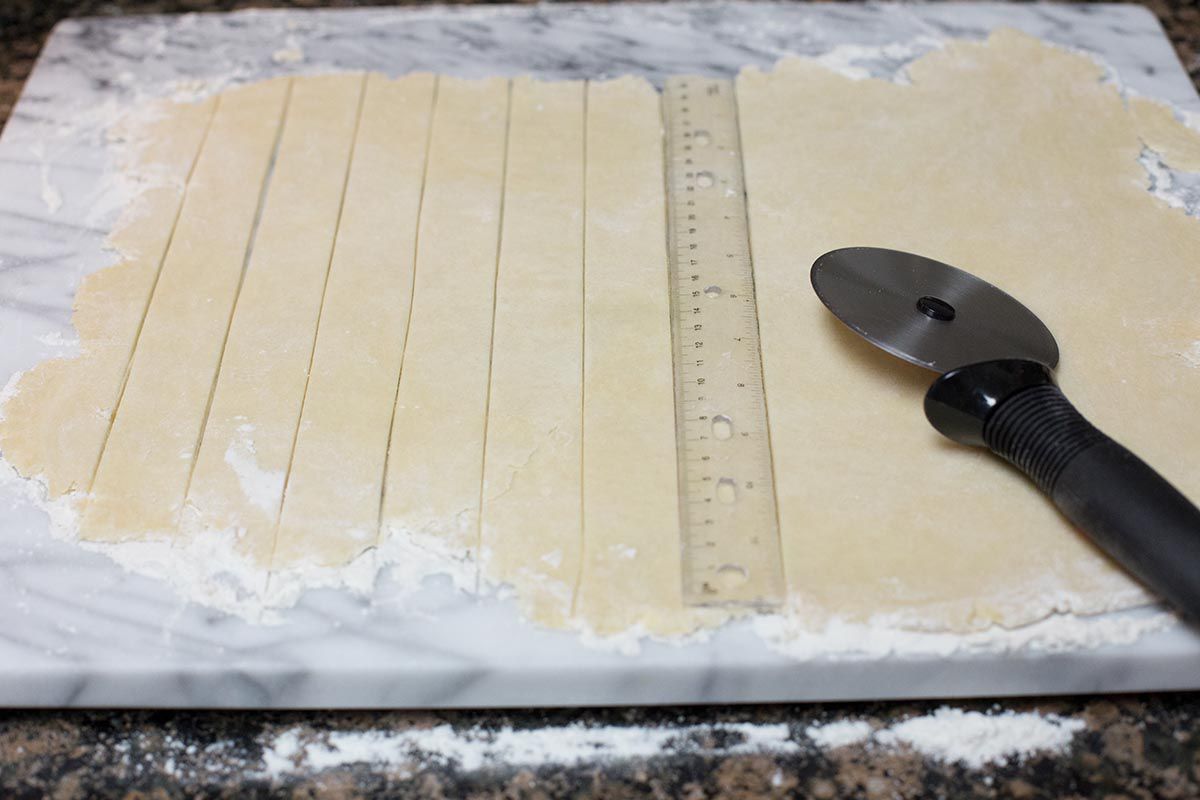 Roll out the top crust for peach pie and slice it into strips for the lattice top