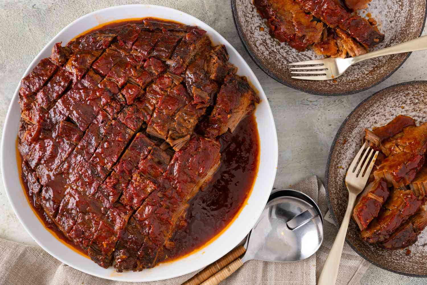 3-ingredient brisket sliced and served on a white plate, with two plates of brisket next to it