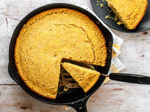 Southern Cornbread in a Skillet with a Piece Cut Out and Another Piece on a Plate
