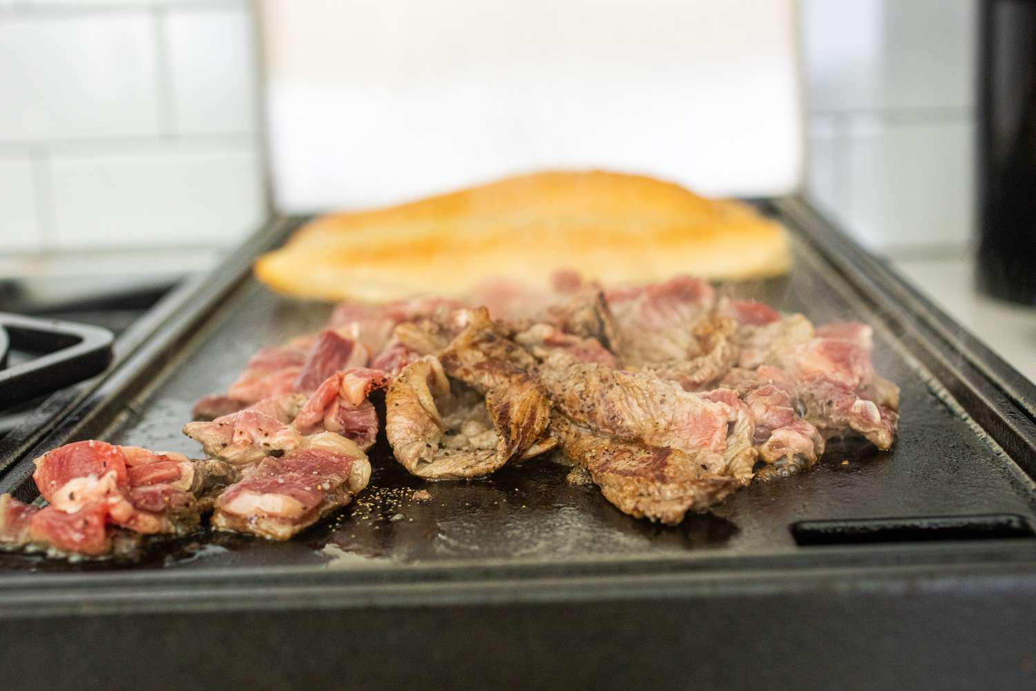 Cooking beef on a griddle for a homemade Philly Cheesesteak.