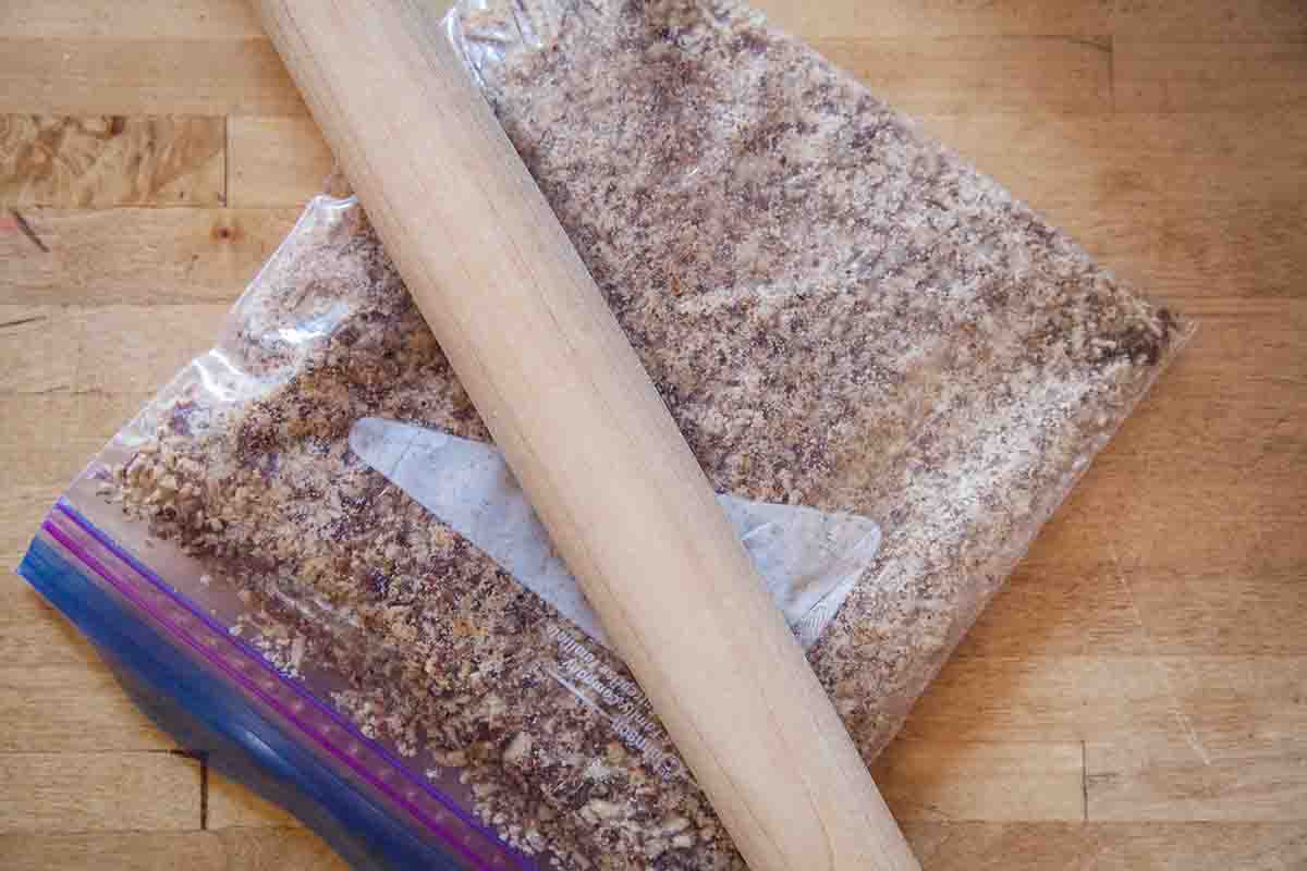 Nuts crushed in a zipper bag with a rolling pin on a wooden surface