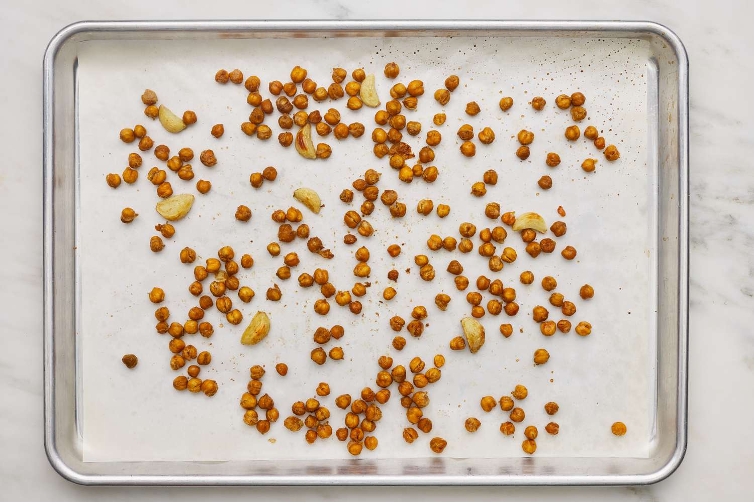 Roasted seasoned chickpeas on a baking sheet for hummus recipe