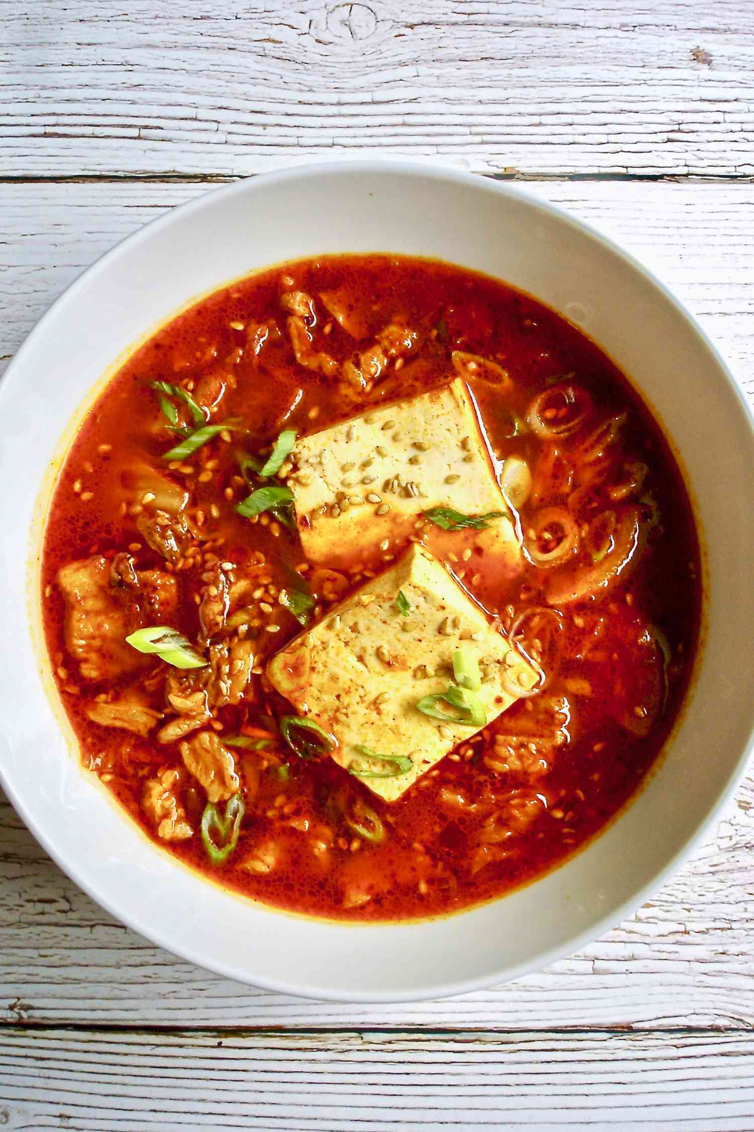 Overhead view of a bowl of spicy kimchi and pork belly stew.