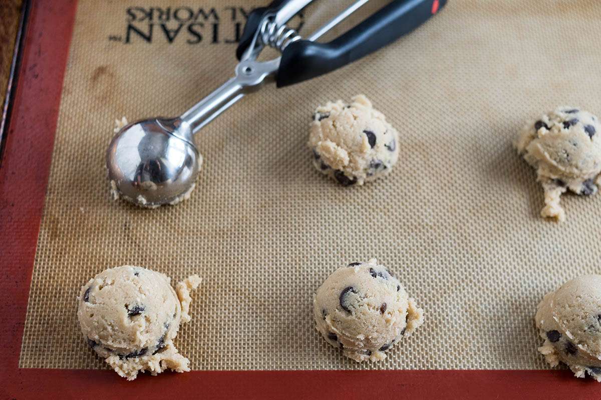 Homemade chocolate chip cookies scooped onto a silpat.