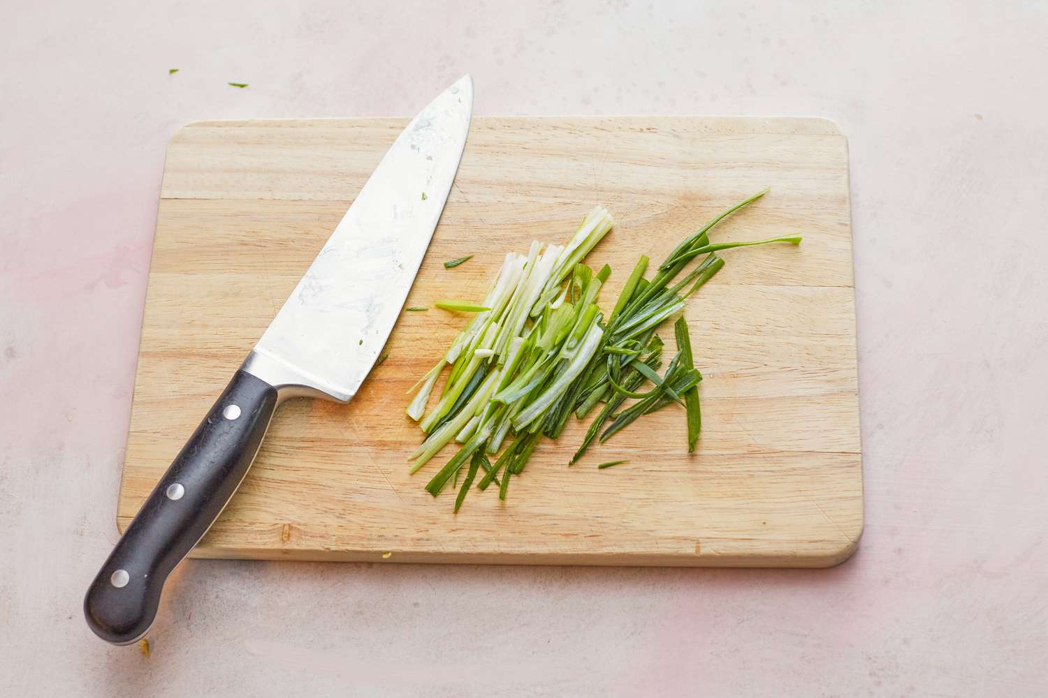 Slicing scallions with a chef's knife to make whole steamed black sea bass