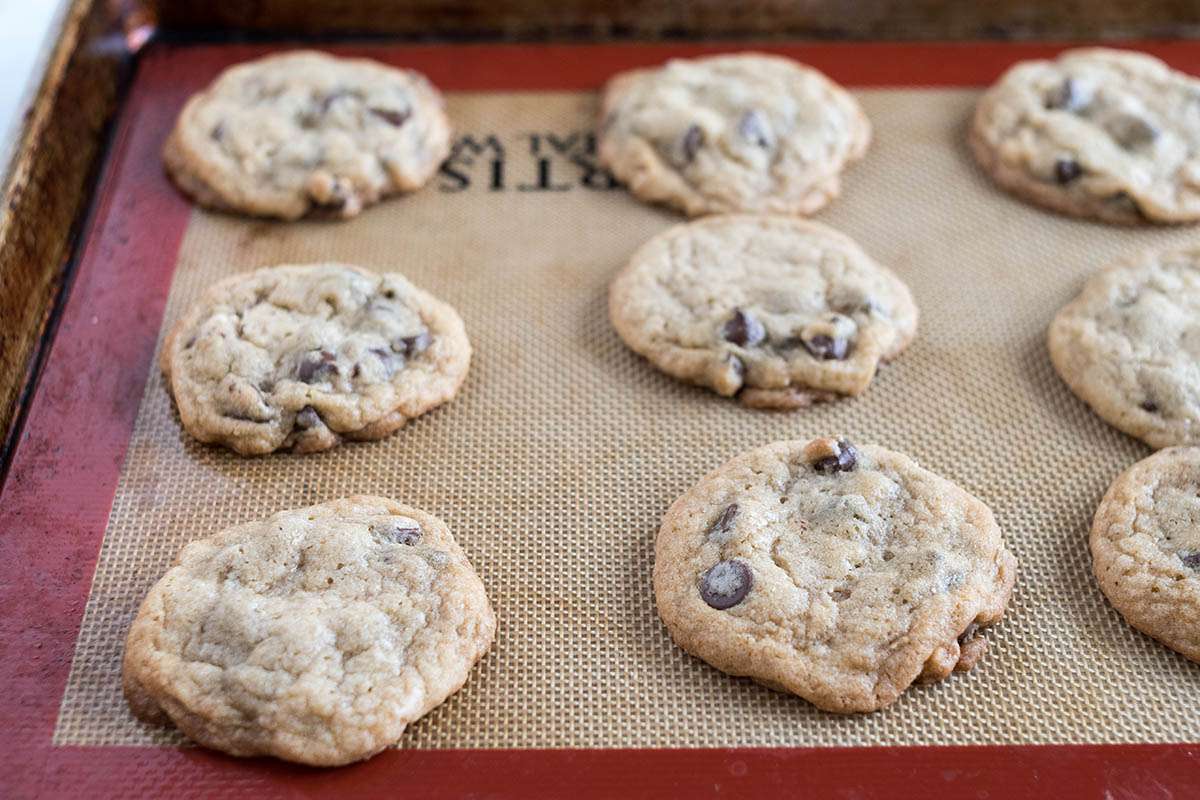 Homemade chocolate chip cookies cooling on a silpat.