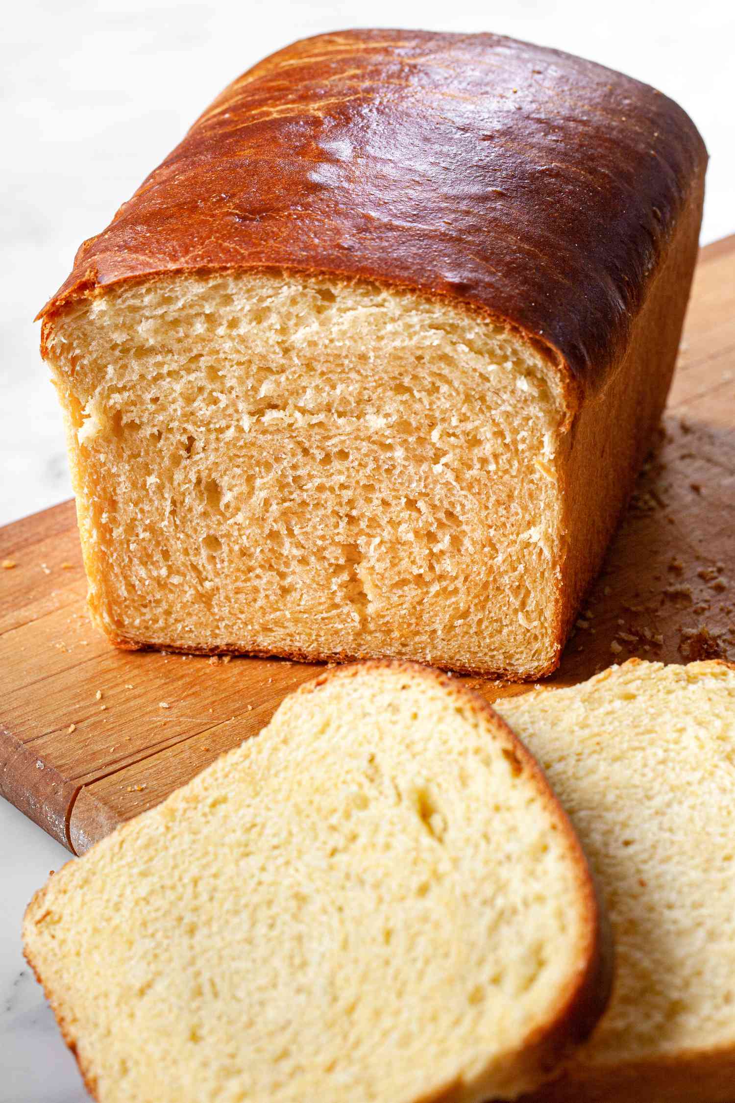 Brioche Sandwich Loaf on a Cutting Board with Slices of Bread Cascading Off the Board onto the Counter