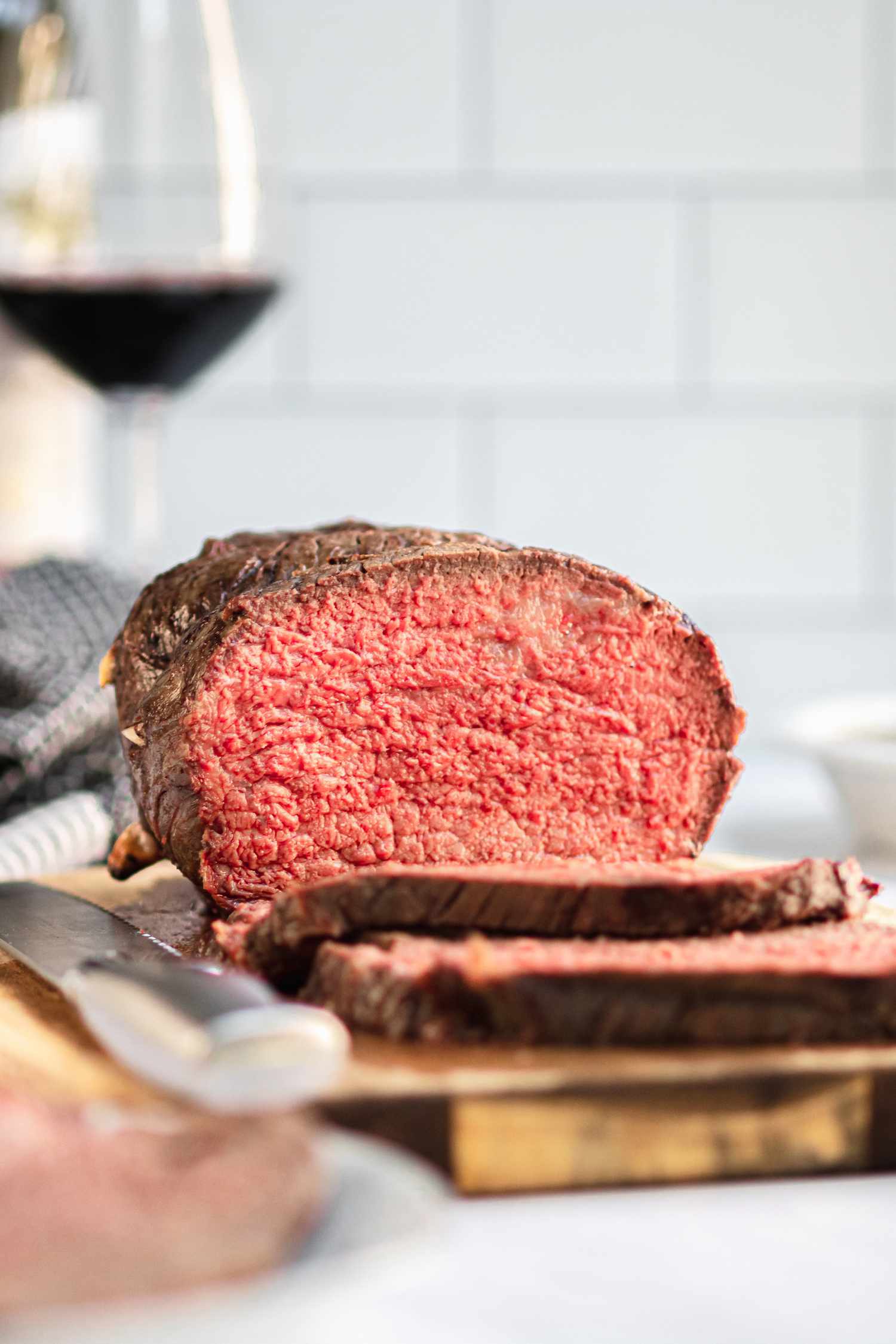 Side view of a medium rare roast beef on a cutting board with a couple slices in front of it.
