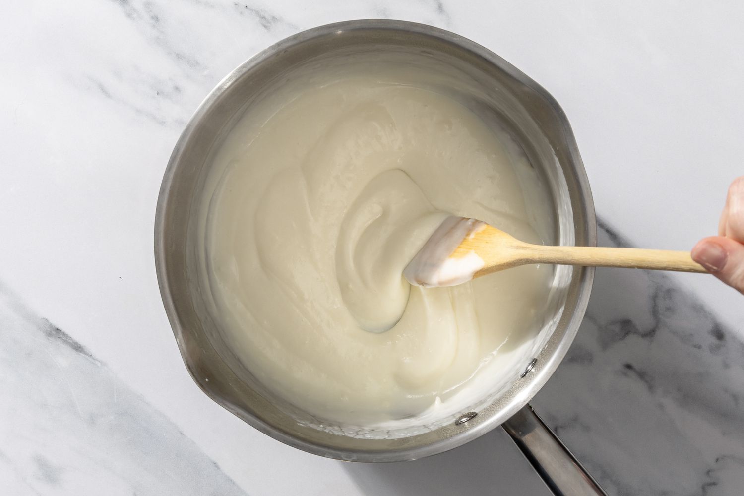 creamy mixture in a pot, hand stirring with wooden spoon for My Mom’s Famous Broccoli Cheese Casserole