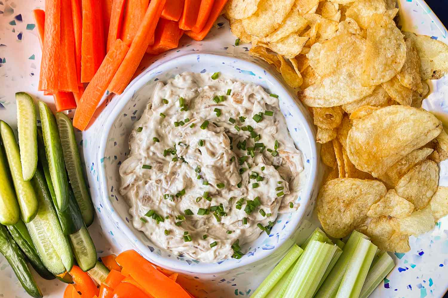 Overhead shot of bowl of Ina Garten's pan fried onion dip surrounded by crudité