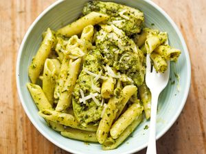 Penne pasta served with pesto garnished with grated cheese