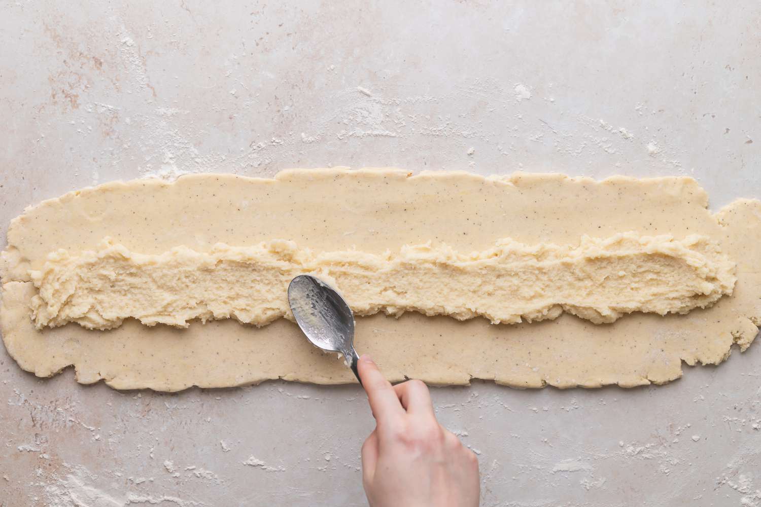 Spreading filling on top of dough to make kringle.