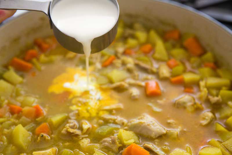 Adding cream to mulligitawny soup in a pot