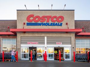 The entrance to a Costco Wholesale store with people entering and exiting marked with prominent signs
