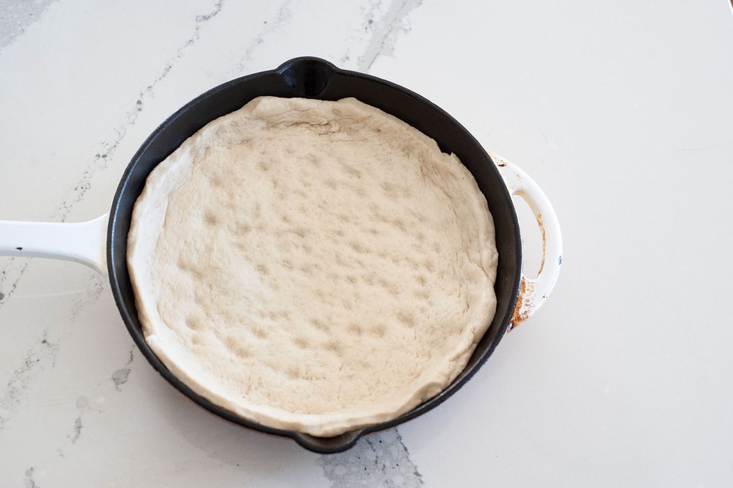 Pizza dough stretched in cast iron skillet.