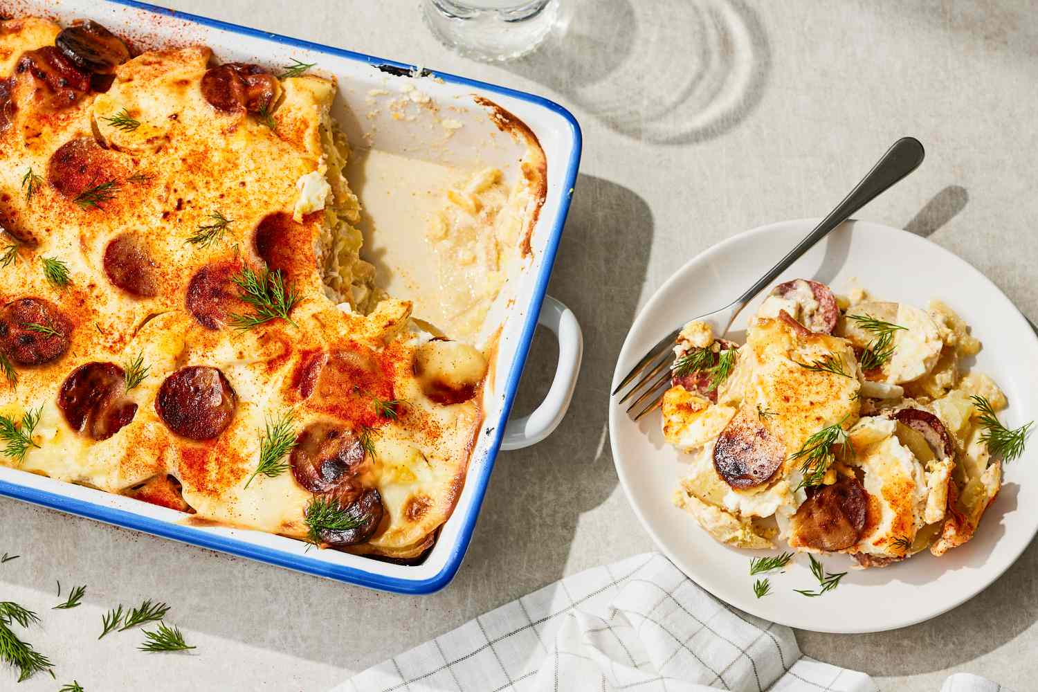 Rakott Krumpli (Hungarian Potato Casserole) in a 9x13 casserole dish, one serving on a plate