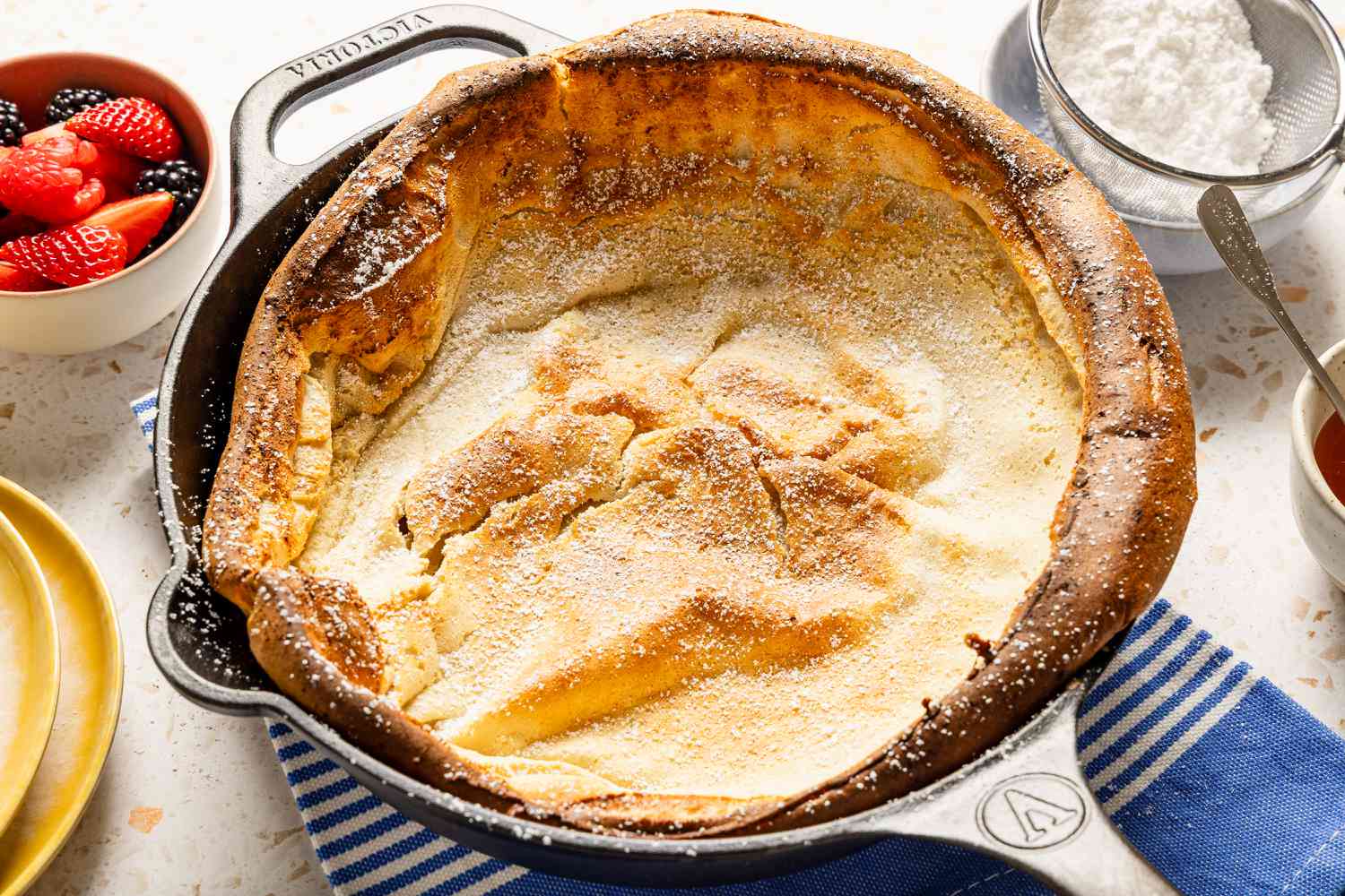 Cooked Dutch baby pancake in a skillet, sprinkled with powdered sugar