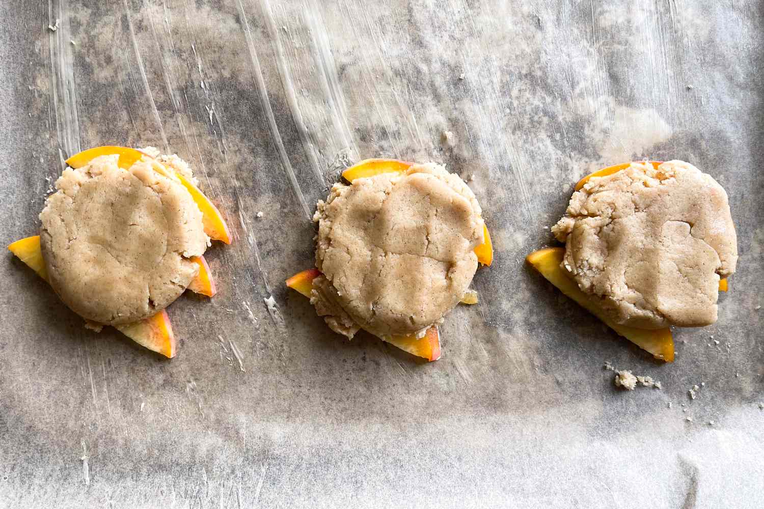 Three unbaked peach upsidedown cookies on parchment paper