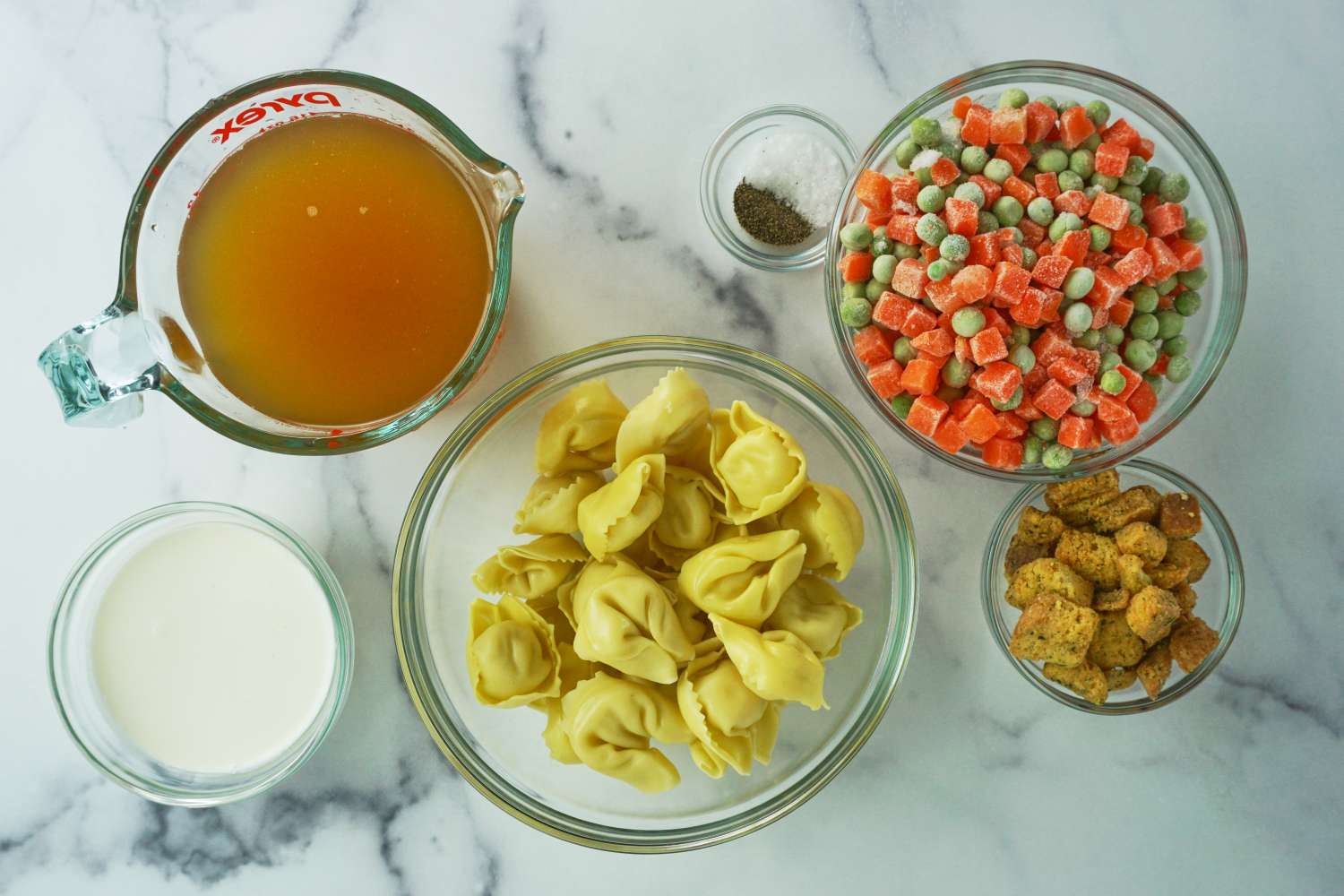 Ingredients for creamy tortellini soup including tortellini broth cream croutons and mixed vegetables