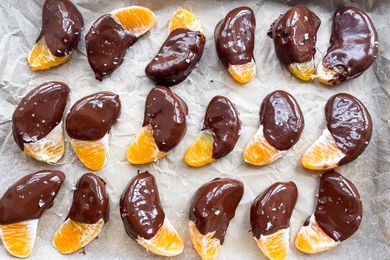 Overhead view of a parchment paper lined pan of orange slices that have been dipped in chocolate and sprinkled with salt