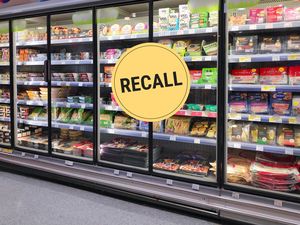 Grocery store refrigerated shelves, yellow recall sign overlay