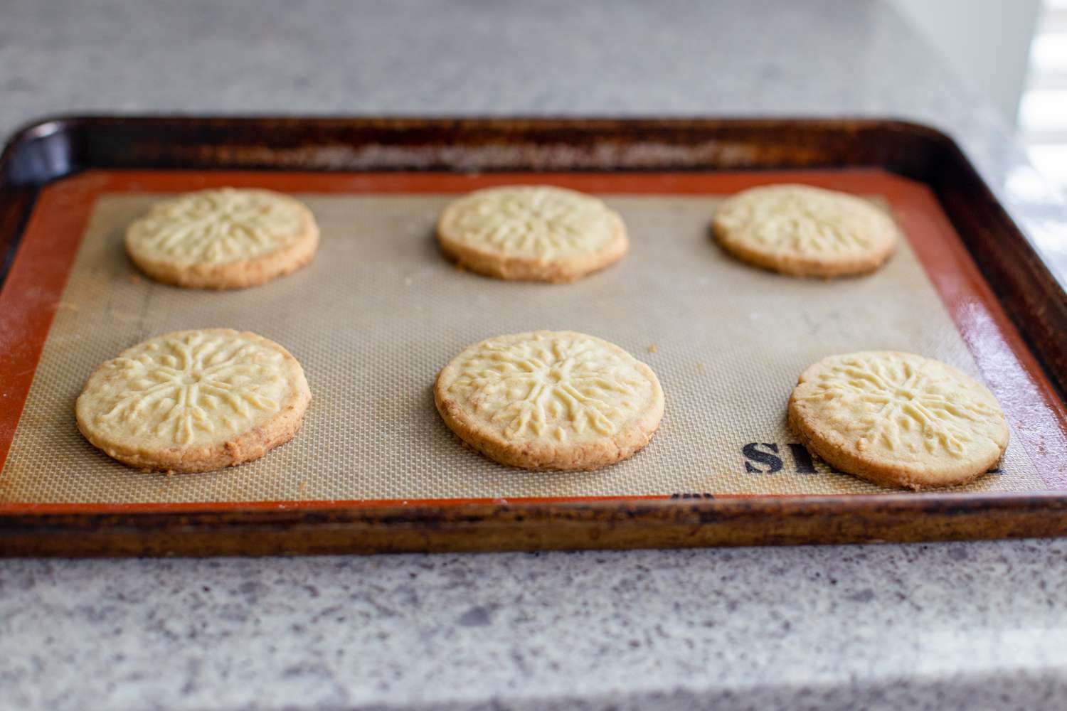 Almond-flavored butter cookies on a baking sheet.