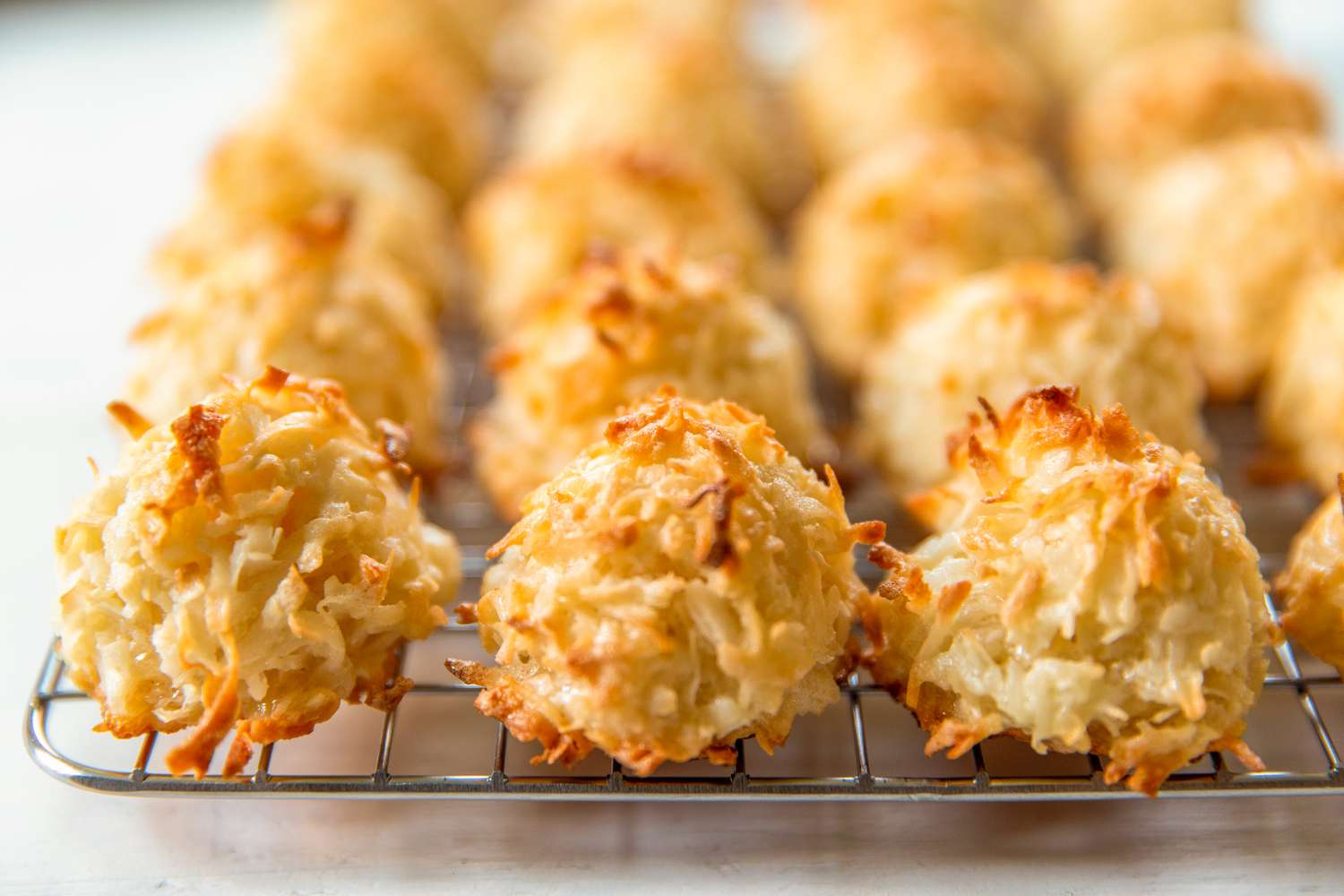 Closeup view of three macaroon cookies on cooling rack with others blurred in the background all on a white background