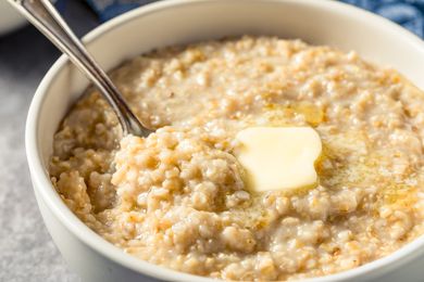 A bowl of oatmeal with a dollop of butter and a spoon
