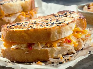 Grilled cheese sandwich filled with kimchi and melted cheese sprinkled with sesame seeds