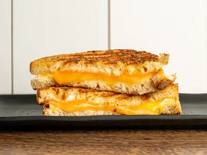 Two halves of a grilled cheese sandwich stacked on a plate