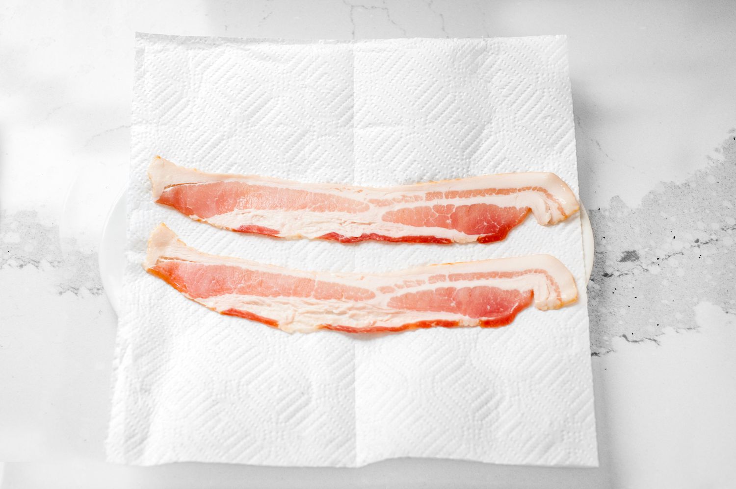 Two Slices of Bacon on a Paper Towel Lined Plate for Microwave Bacon Recipe